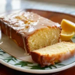 Slice of old-fashioned lemon pound cake on a plate with fresh lemons